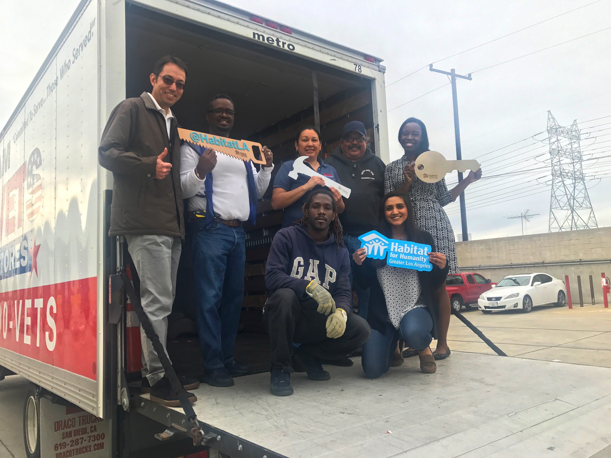 Habitat LA staff and ReStore volunteers with AMVETS representatives on the ramp of a truck posing for a group photo.