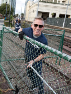 Carl Jordan working on a fence in a neighborhood smiling for a photo.